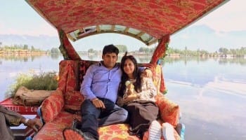 Romantic couple enjoying a Shikara ride on Dal Lake during a Kashmir honeymoon with snow-capped mountains in the background